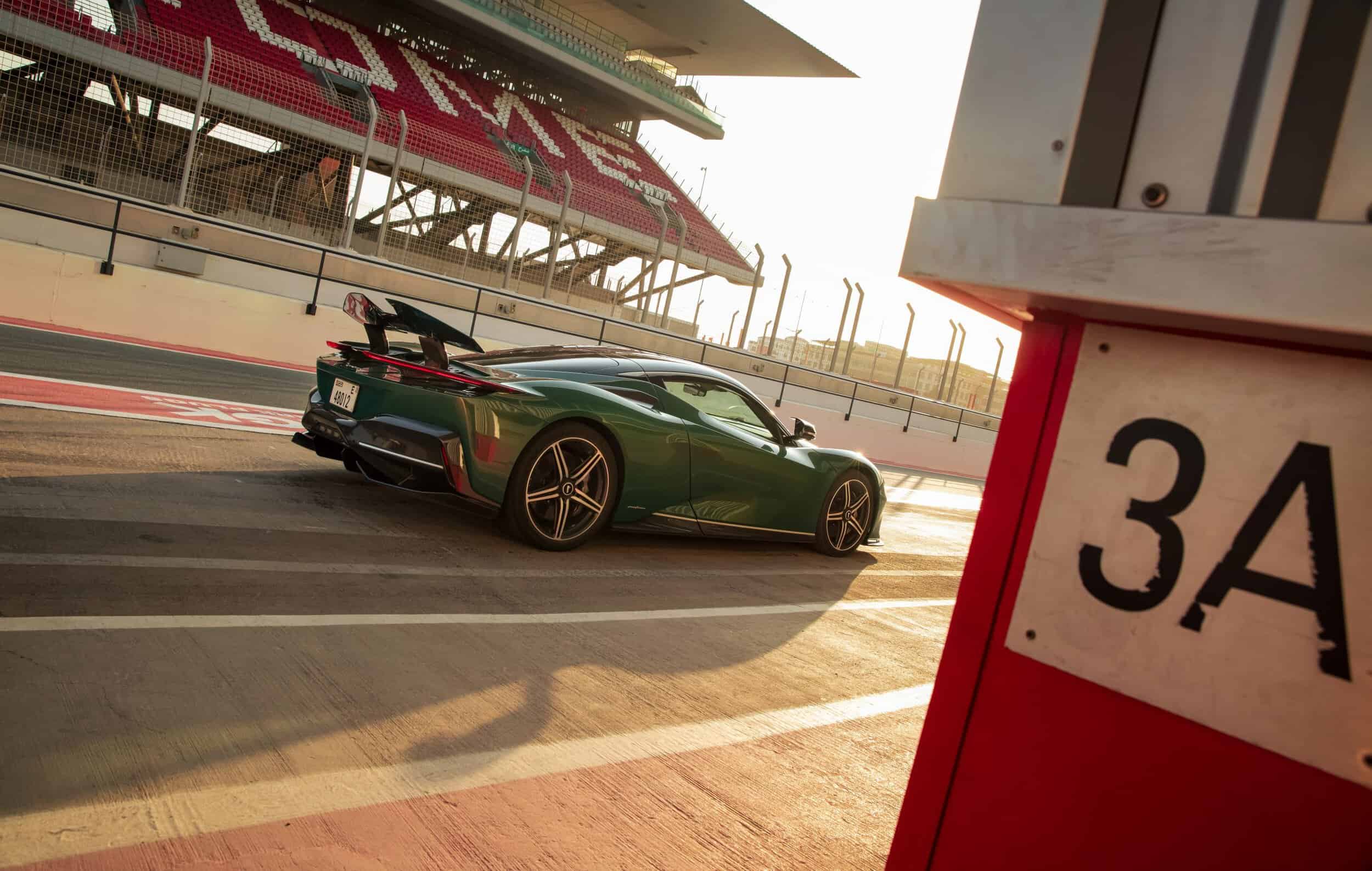 Luxurious green sports car with high-performance features at a racing circuit.