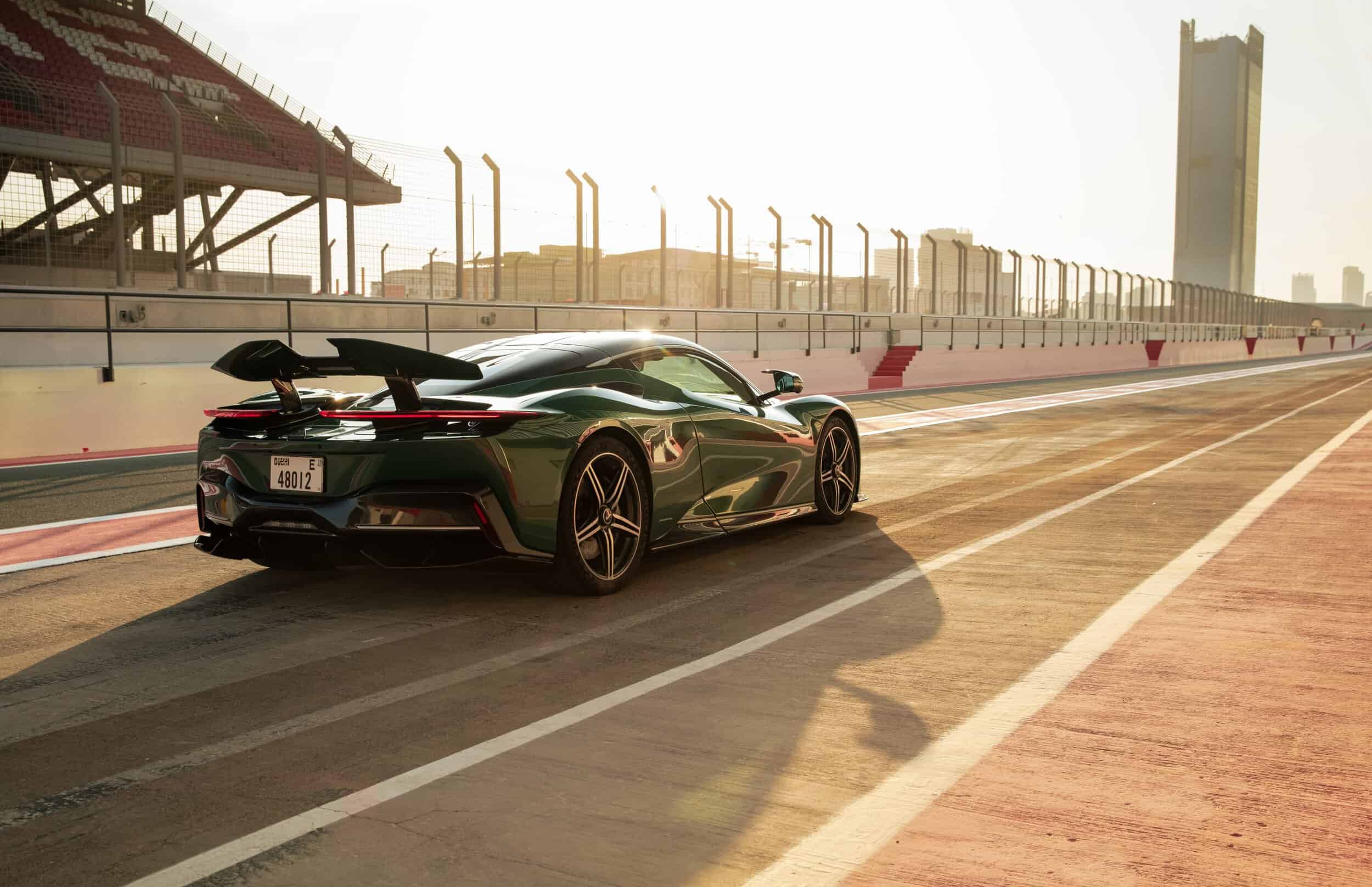 Luxurious green sports car on a race track with city skyline in background.