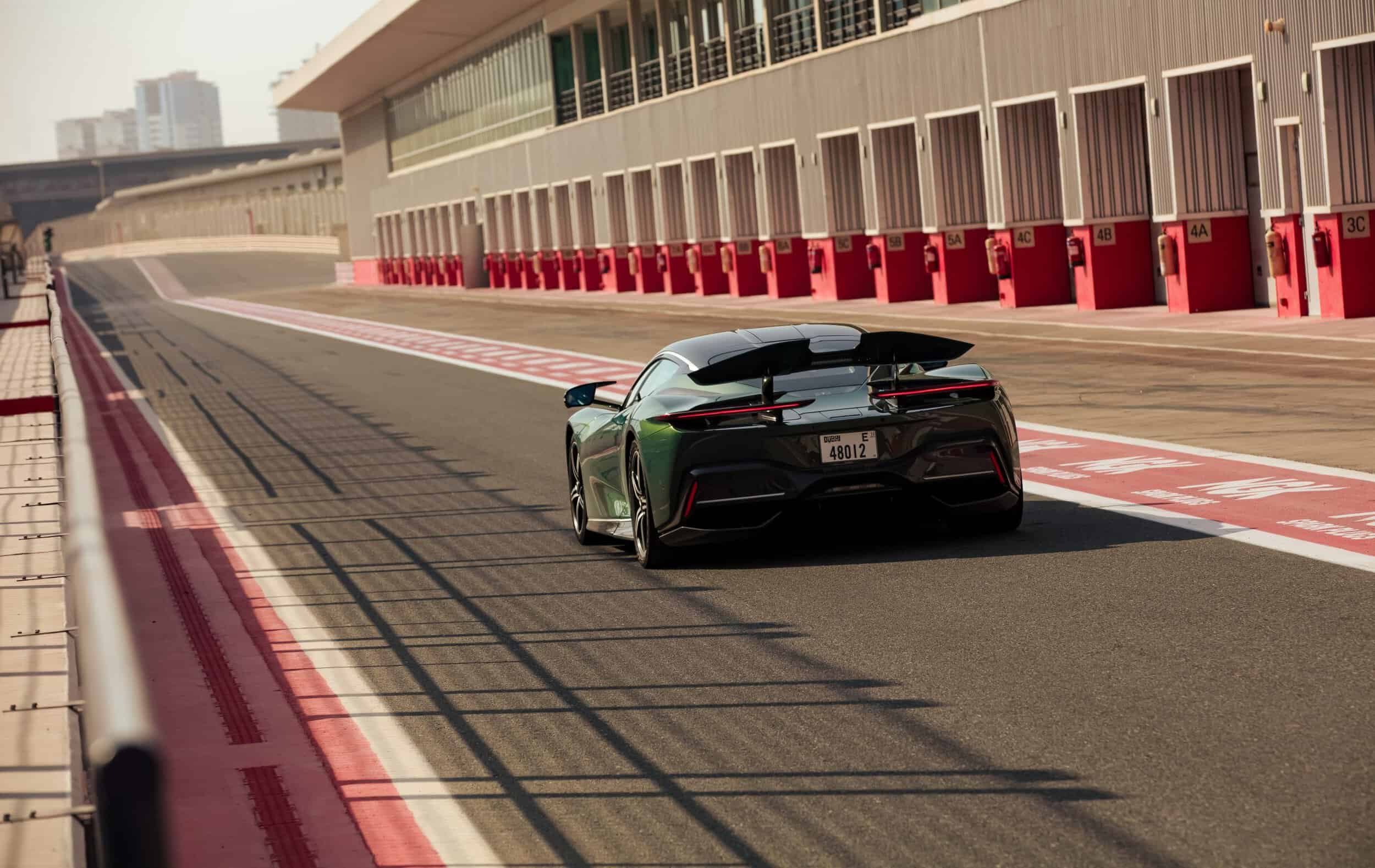 High-performance sports car on racing circuit with modern architecture background.
