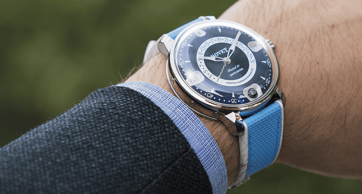 Elegant Bovet timepiece with blue strap on a man's wrist, showcasing intricate dial details.